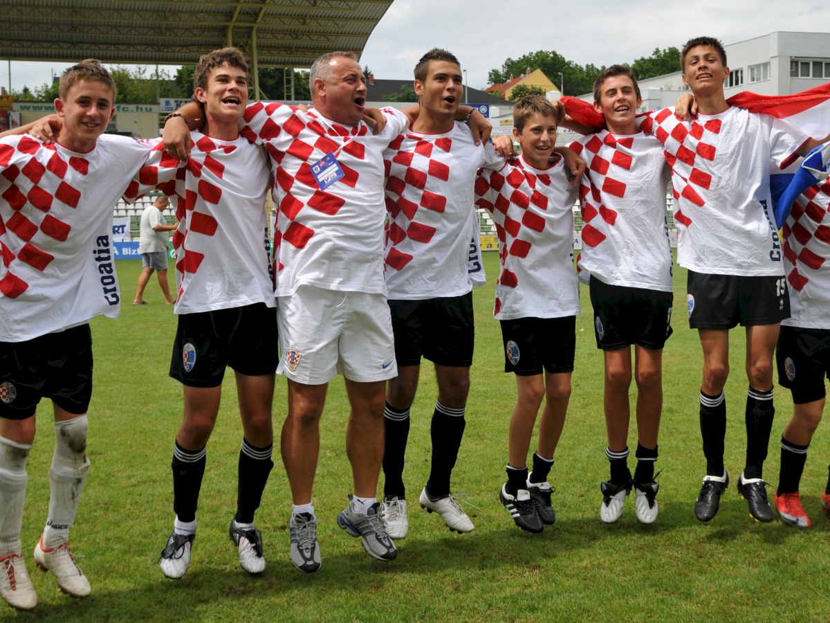 A group of people wearing checkered jerseys, likely celebrating on a grassy field with their arms around each other.