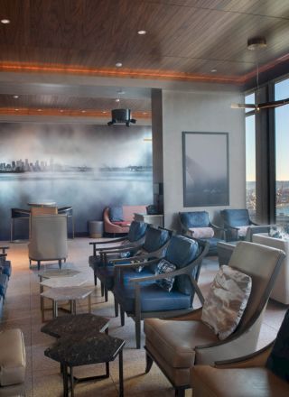 A modern lounge area with leather chairs, large windows offering a waterfront view, and a wall mural of a city skyline, ending the sentence.
